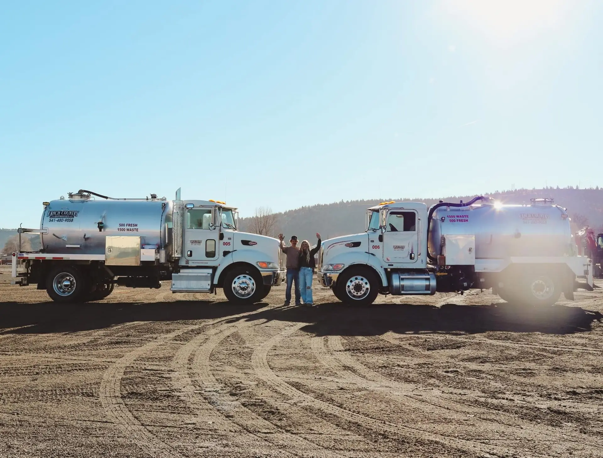 Two Ranch Country Outhouses vacuum trucks parked nose to nose with two crew members waving